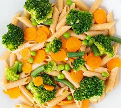 Whole wheat pasta Penne with broccoli, carrots, green peas. Close-up, macro. Diet menu