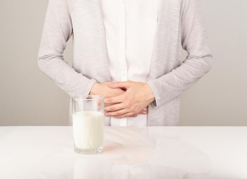 Woman next to glass of milk having bad stomach ache.