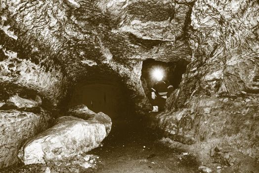 Miner man underground in a mine tunnel.  Worker in overalls, safety helmet