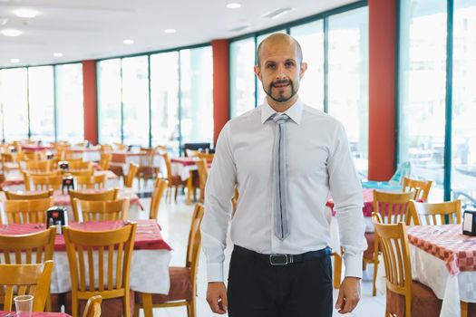 Young handsome administrator standing inside restaurant