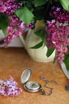 Antique pocket watch, flower in front of wooden background.