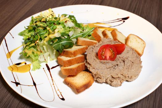 Slice of toasted bread and liver pate on white plate