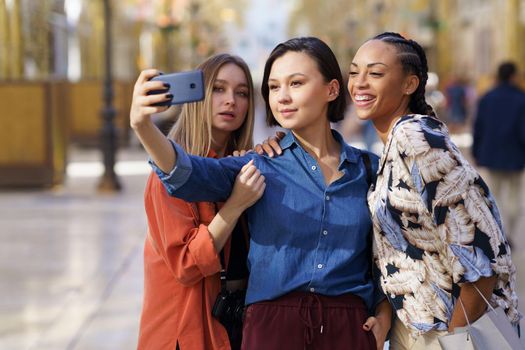 Trendy girlfriends taking selfie on street