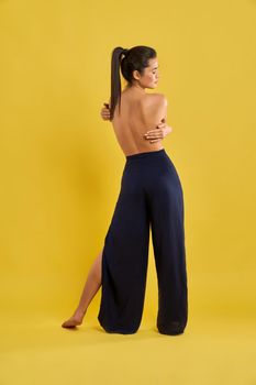 Girl with bare back standing backwatds, holding by hands.