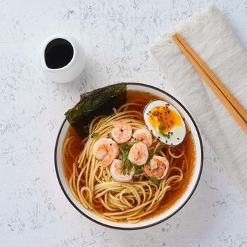 Asian soup with noodles, ramen with shrimps. White stone table, top view