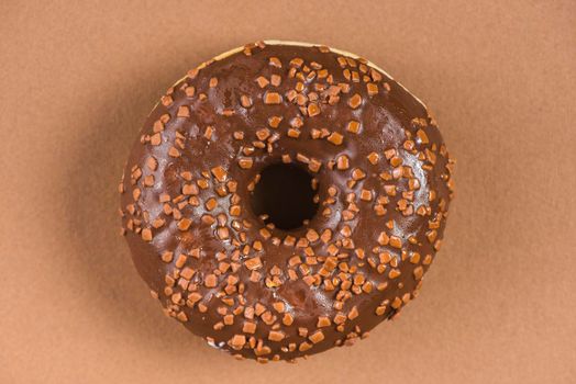 dark chocolate doughnut with sprinkles brown background