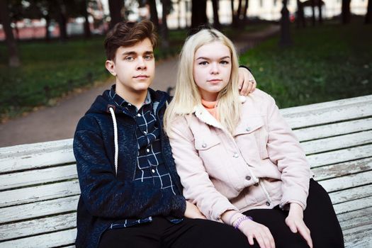 teenagers in love sit on a Park bench in autumn and stare straight ahead