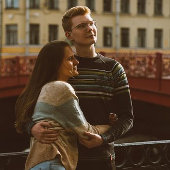 Man and woman stand on a bridge in the center of the city and look up in one direction. Boy and girl dream and think. The concept of teenage love, the first serious relationship, the difficulties of adolescence