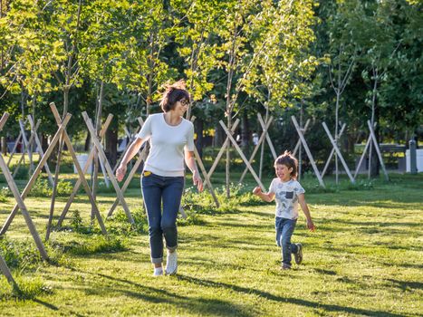 Family life. Mother and son play in park. Summer vibes. Active outdoor game. Lifestyle. Leisure activity open air.