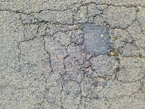 Asphalt surfaces of damaged streets and roads with cracks in a close up.