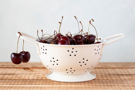Fresh cherries in a white enamel strainer