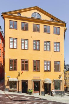 STOCKHOLM, SWEDEN - July 06, 2017. Shop with old maps with open doors. Sun reflections on bright yellow walls in Gamla stan. Colorful old fashioned buildings in historical part of town.