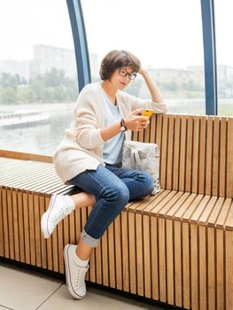 Smiling woman in eyeglasses texting on smartphone. Millennials lifestyle. Casual clothes.