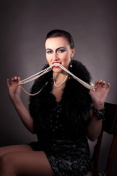 woman with vintage make-up take pearls in teeth