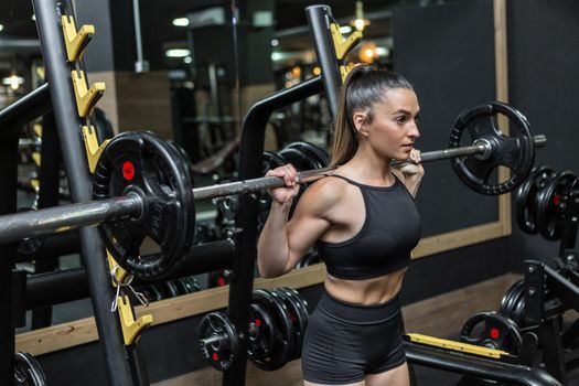 Determined sportswoman doing weightlifting workout with barbell