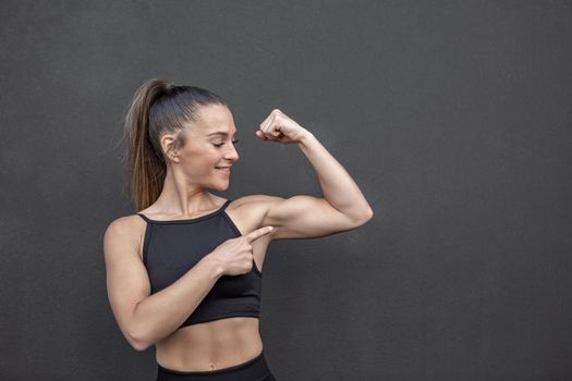 Muscular female athlete pointing at bicep