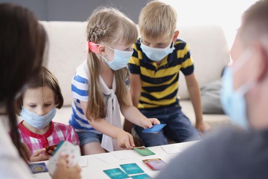 Kids in face masks, prevent virus spread in kindergarten, developing card game