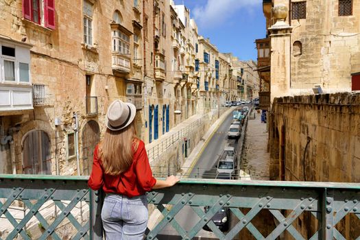 Traveler girl on iron bridge looking historic buildings in city centre of Valletta, Malta
