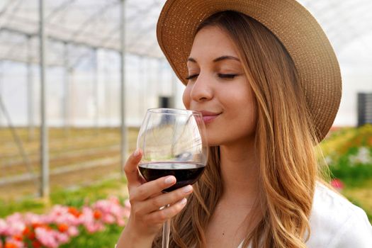 Close-up of beautiful woman smelling red wine from glass with closed eyes
