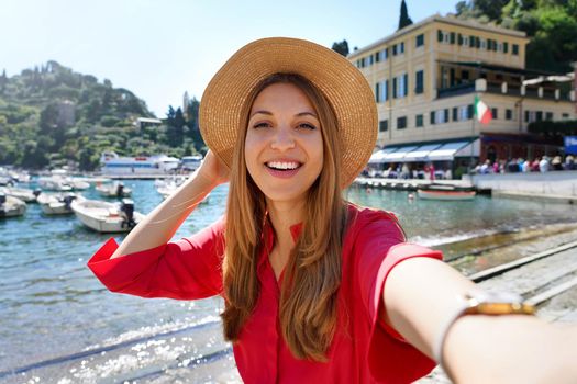 Portofino tourist girl taking selfie photo on famous luxury destination. European tourism attraction in Italy. Young woman on vacation.