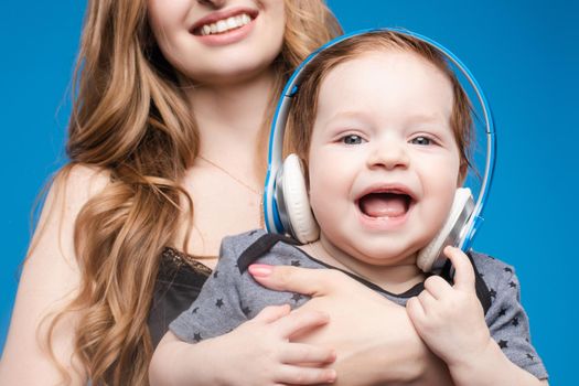 Happy woman with baby boy in headphones.