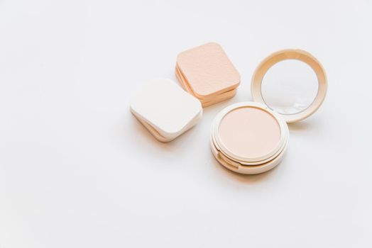 close up cosmetic realistic plastic compact powder with sponges white backdrop