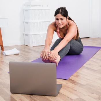 woman doing yoga with laptop