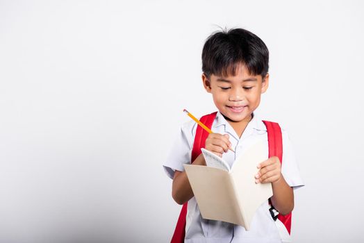 Asian toddler smiling happy wear student thai uniform red pants holding pencil for writers notebook