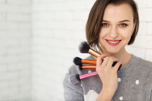smiling woman with makeup brushes