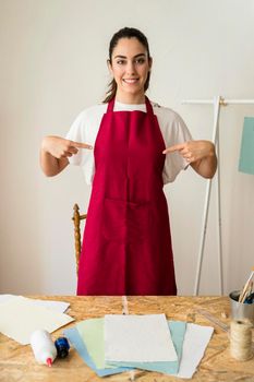 portrait smiling young woman pointing fingers her red apron