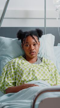 Portrait of young patient in bed with IV drip bag