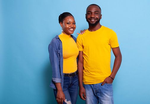 Smiling couple standing in embrace over blue background