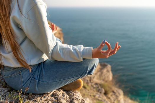 yoga, gesture and healthy lifestyle concept - hand of meditating yogi woman showing gyan mudra over sea sunset background