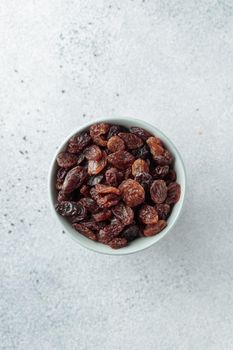 Bowl with raisins on concrete background