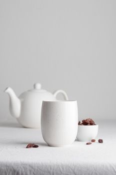 White teacup with raisins and teapot