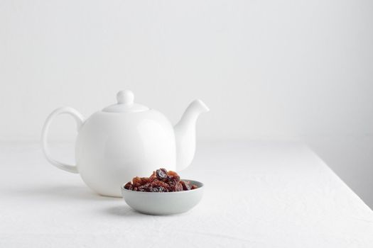 White teapot with raisins on a table