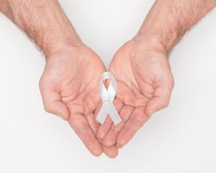 White awareness ribbon. Lung cancer awareness white ribbon bow on man hands. Anti violence against women. Medical and political awareness symbol. Healthcare concept. Political movement concept