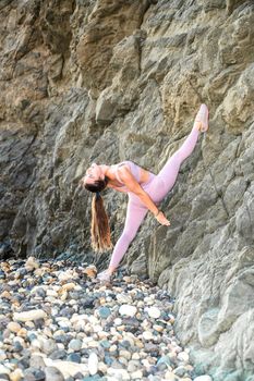 Girl gymnast is training on the beach by the sea. Does twine. Photo series