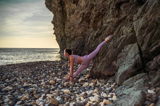 Girl gymnast is training on the beach by the sea. Does twine. Photo series