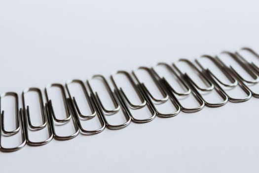 Metal paper clips on white background. Side view.