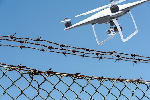 Drone with digital camera flying over a barbed wire fence