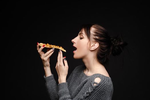 Hungry girl with opened mouth eating pizza