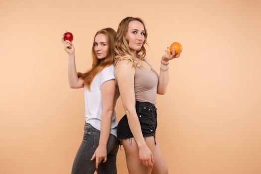Two sporty girls posing with useful vegetables and fruits