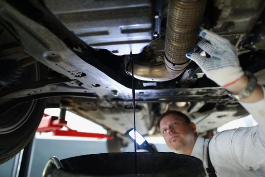 Mechanic man change oil under auto, car maintenance service, oil dripping
