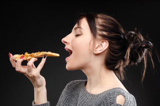 Hungry girl with opened mouth eating pizza