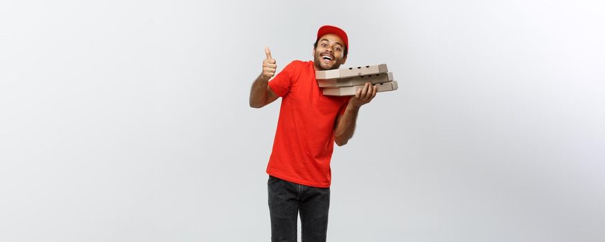 Delivery Concept - Portrait of Handsome African American Pizza delivery man showing thump up. Isolated on Grey studio Background. Copy Space.