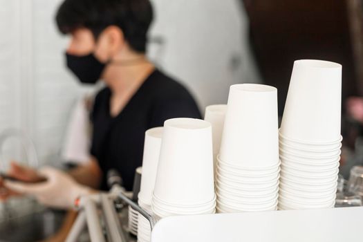 A lot of white disposable paper cups on coffee machine with cofe shop background. The stack of paper cup in the cafe. close up recycle white paper cups on coffee machine