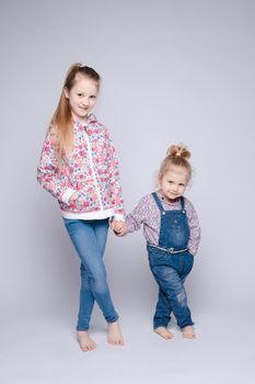 Front view of two pretty kids keeping hands and posing