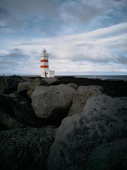 Lighthouse with red stripes wide angle over the black rocks