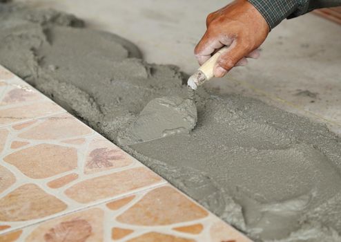 handyman laying tile, trowel with mortar